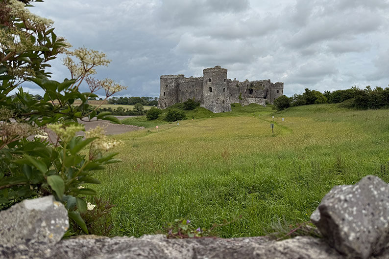 Uitzicht op Carew Castle in Zuid-Wales vanaf het wandelpad – hondvriendelijk kasteel in groen landschap