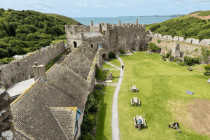 Binnenplaats van Manorbier Castle in Pembrokeshire, Wales, met uitzicht op zee en bezoekers met hond op het grasveld