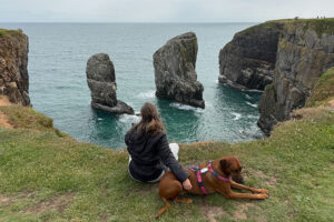 Vrouw met hond bij de Elegug Stacks in Pembrokeshire. Samen op reis in Wales
